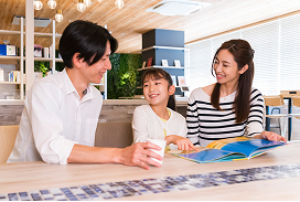 両親と子供がカフェで読書をしている様子。
