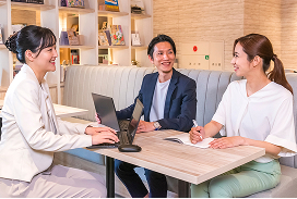 カフェのテーブル席でスーツ姿の女性と男性が打ち合わせをしている様子。