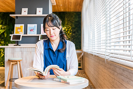 女性が窓際のテーブル席で読書をしている。