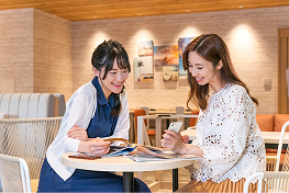 2人乗女性が向かい合う席に座り一緒に読書をしている。