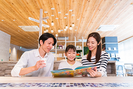 両親と子供がカフェで読書をしている様子。