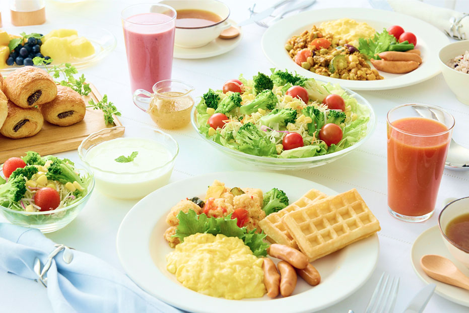 サラダ、ワッフル、スクランブルエッグ、ジュースなどが並ぶ朝食プレート。