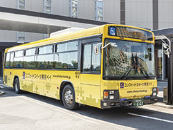 ⑥「送迎バス専用乗降場」看板付近でお待ちください。乗車いただくのは黄色いシャトルバスです。
