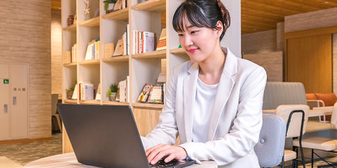明るいカフェスペースで仕事をするスーツ姿の女性