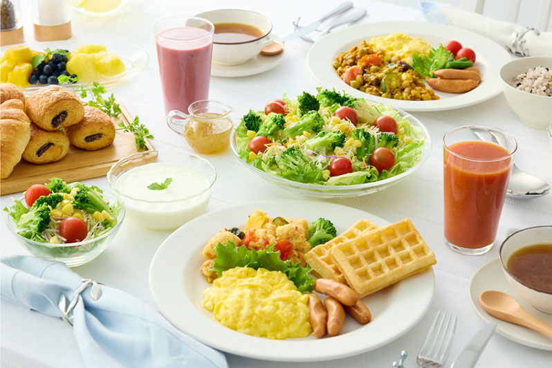サラダ、ワッフル、スクランブルエッグ、ジュースなどが並ぶ朝食プレート。